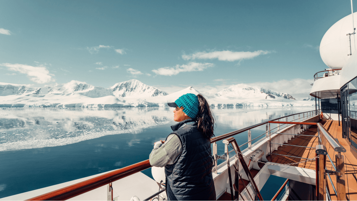 A woman on a cruise ship looking out at icebergs